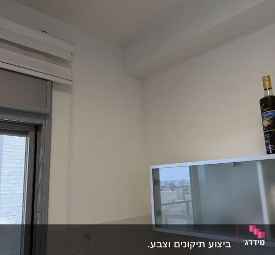 צביעה נקייה וחלקה של קיר ותקרה בצבע לבן באזור החלון